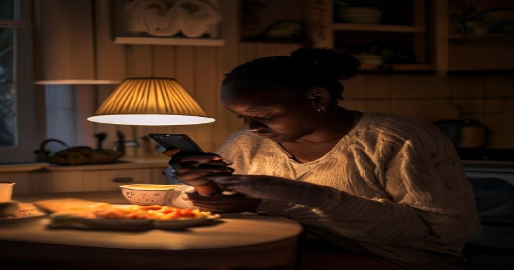 South African woman sitting alone at night eating comfort food in front of her phone, illustrating emotional eating